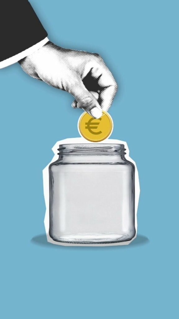 Main déposant une pièce d’euro dans un bocal vide, symbolisant l'investissement et l'épargne.