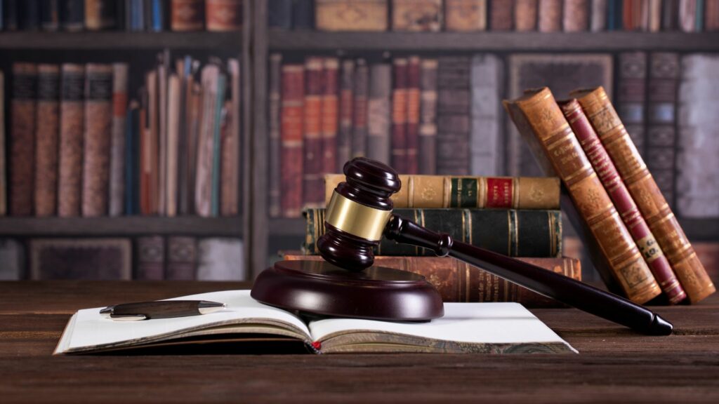 Marteau de justice posé sur un livre ouvert devant une bibliothèque, symbolisant la réglementation et les lois sur la protection des données.