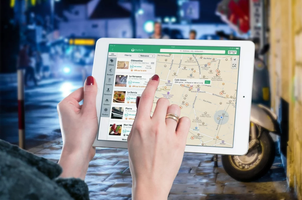 Femme utilisant une tablette pour chercher un restaurant sur une application de carte interactive.