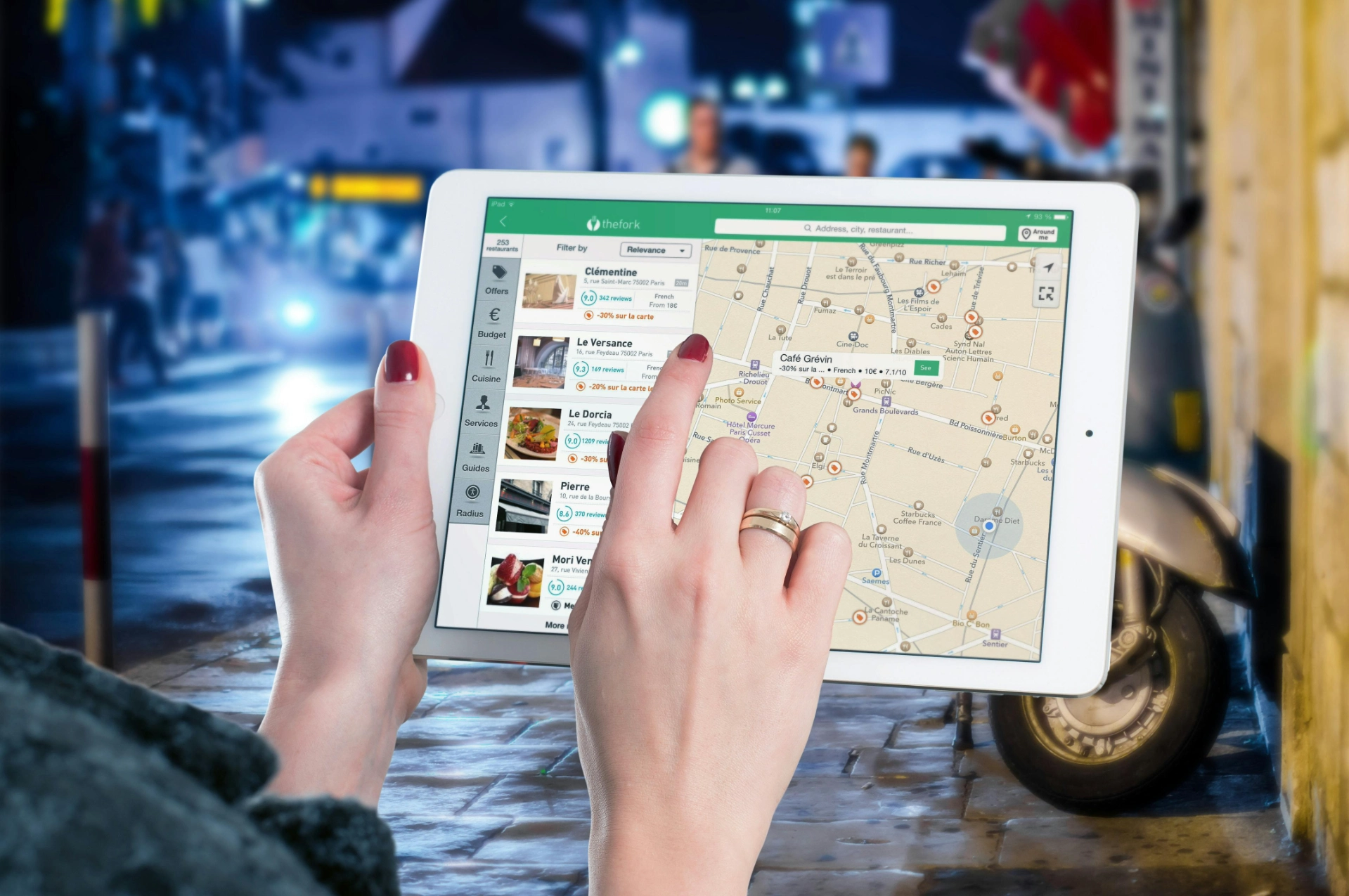 Femme utilisant une tablette pour chercher un restaurant sur une application de carte interactive.