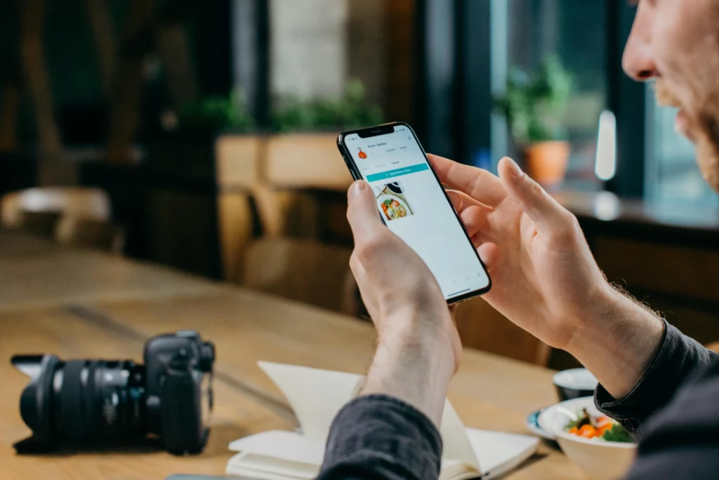 Personne utilisant une application mobile de livraison de repas sur son smartphone dans un café.
