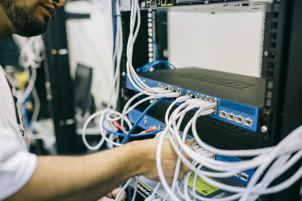 Technicien connectant des câbles réseau dans un serveur informatique.