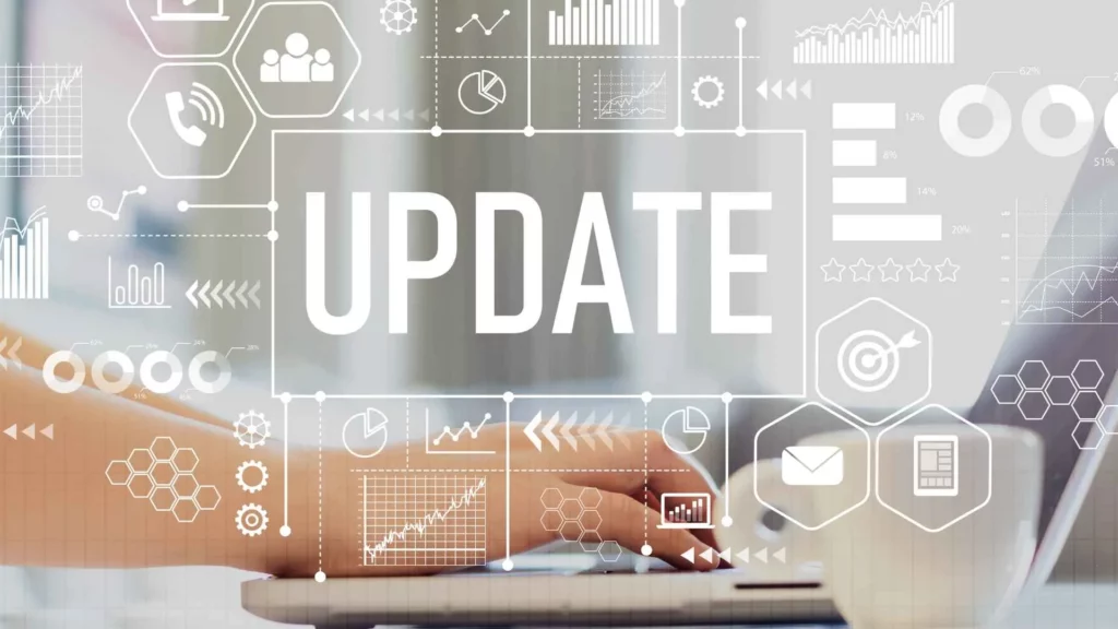 Mot « UPDATE » superposé à des icônes numériques sur fond de mains tapant au clavier.
