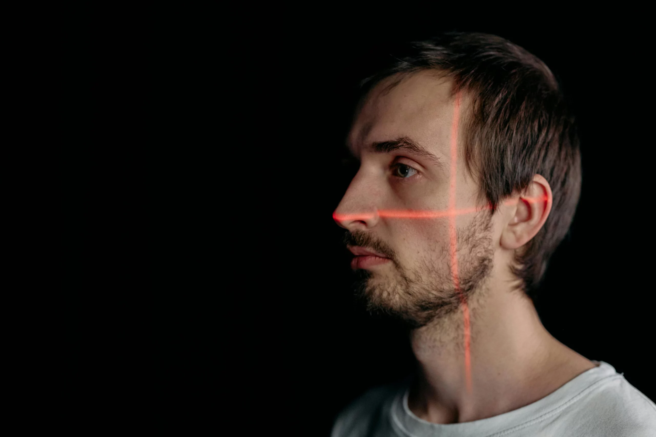 Reconnaissance faciale avec projection de lignes laser rouges sur le visage d’un homme.