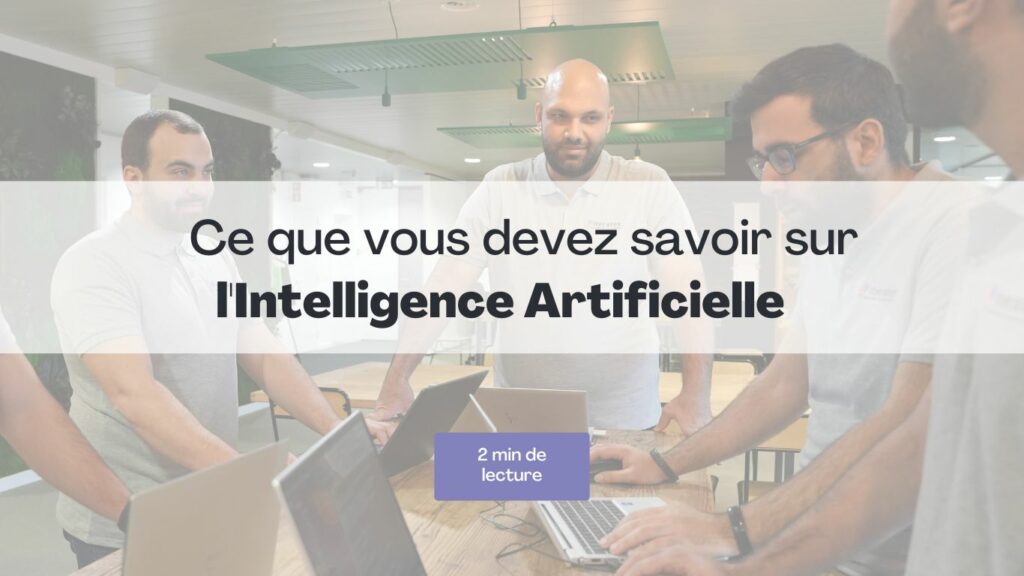Quatre membres d’équipe discutent autour d’un ordinateur avec le texte « Ce que vous devez savoir sur l’Intelligence Artificielle ».