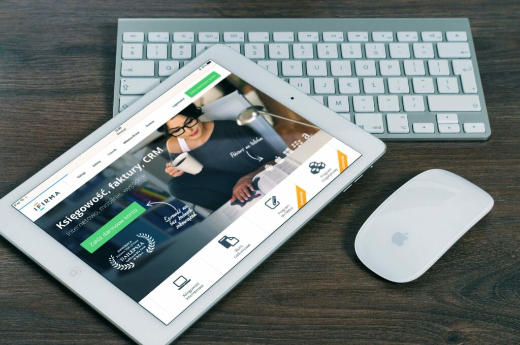 Tablette affichant un site de comptabilité en ligne en polonais, posée devant un clavier Apple.