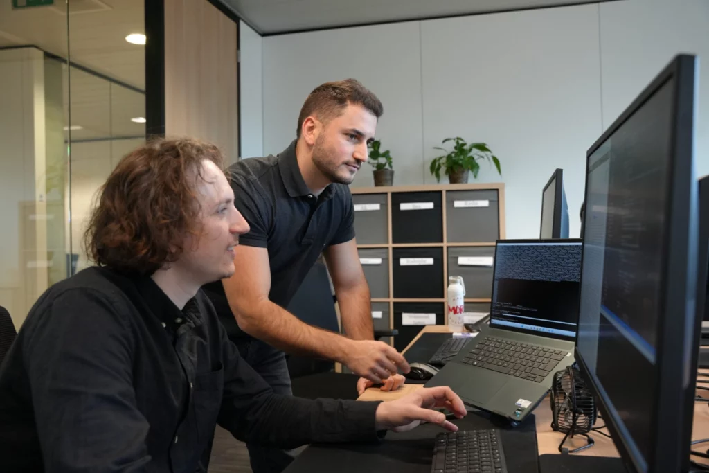 Deux développeurs collaborent sur une application sur mesure dans un bureau moderne.