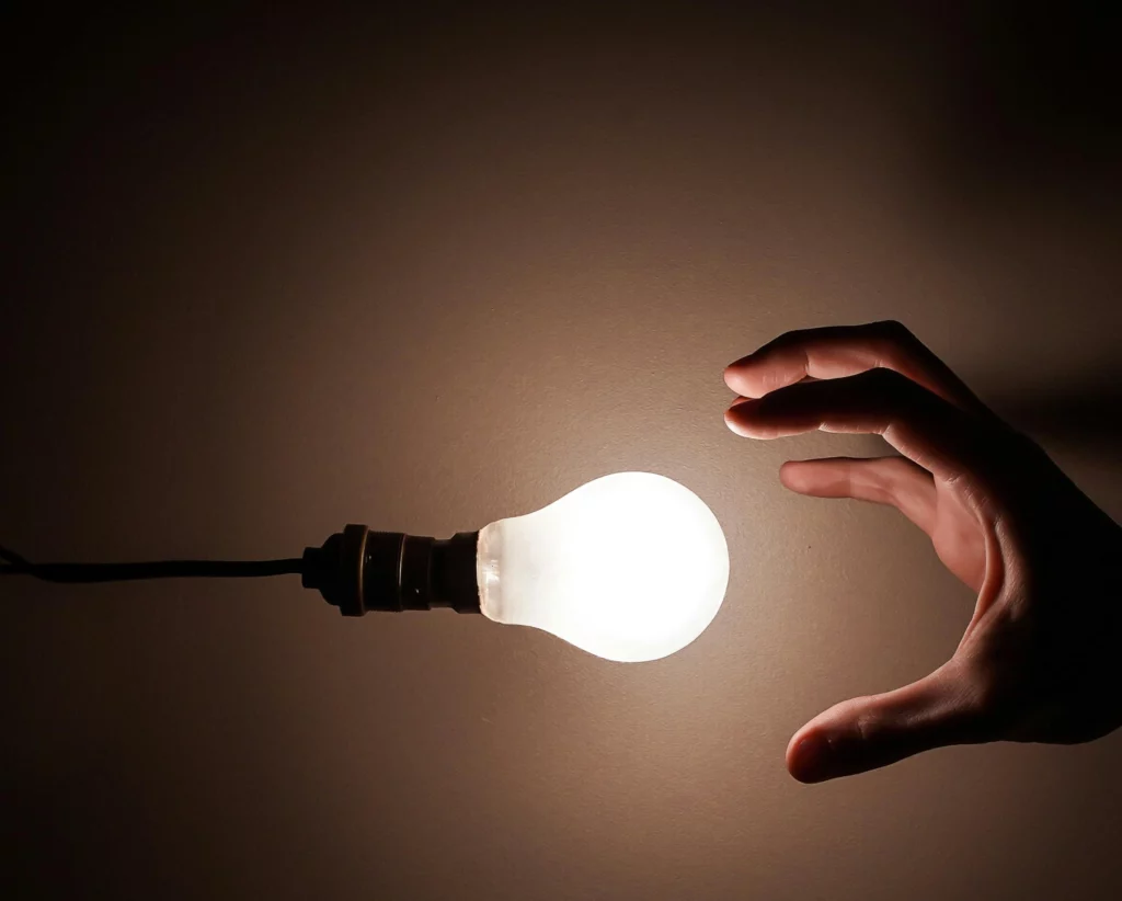 Hand stretched out towards a light bulb, symbolising the idea of creation or innovation. Hand stretched out towards a light bulb, symbolising the idea of creation or innovation.