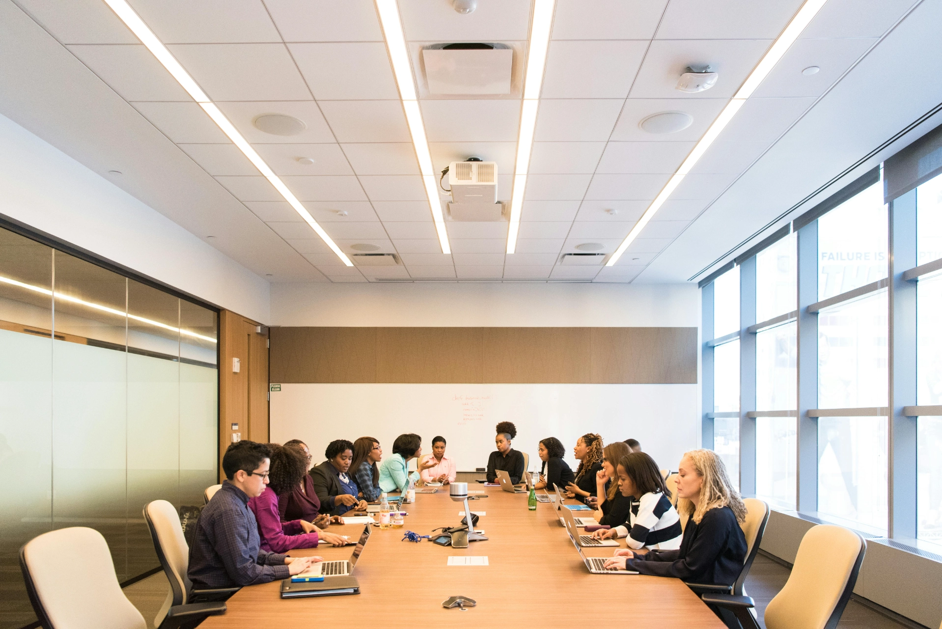Réunion d’équipe autour d’une grande table de conférence dans une salle lumineuse.
