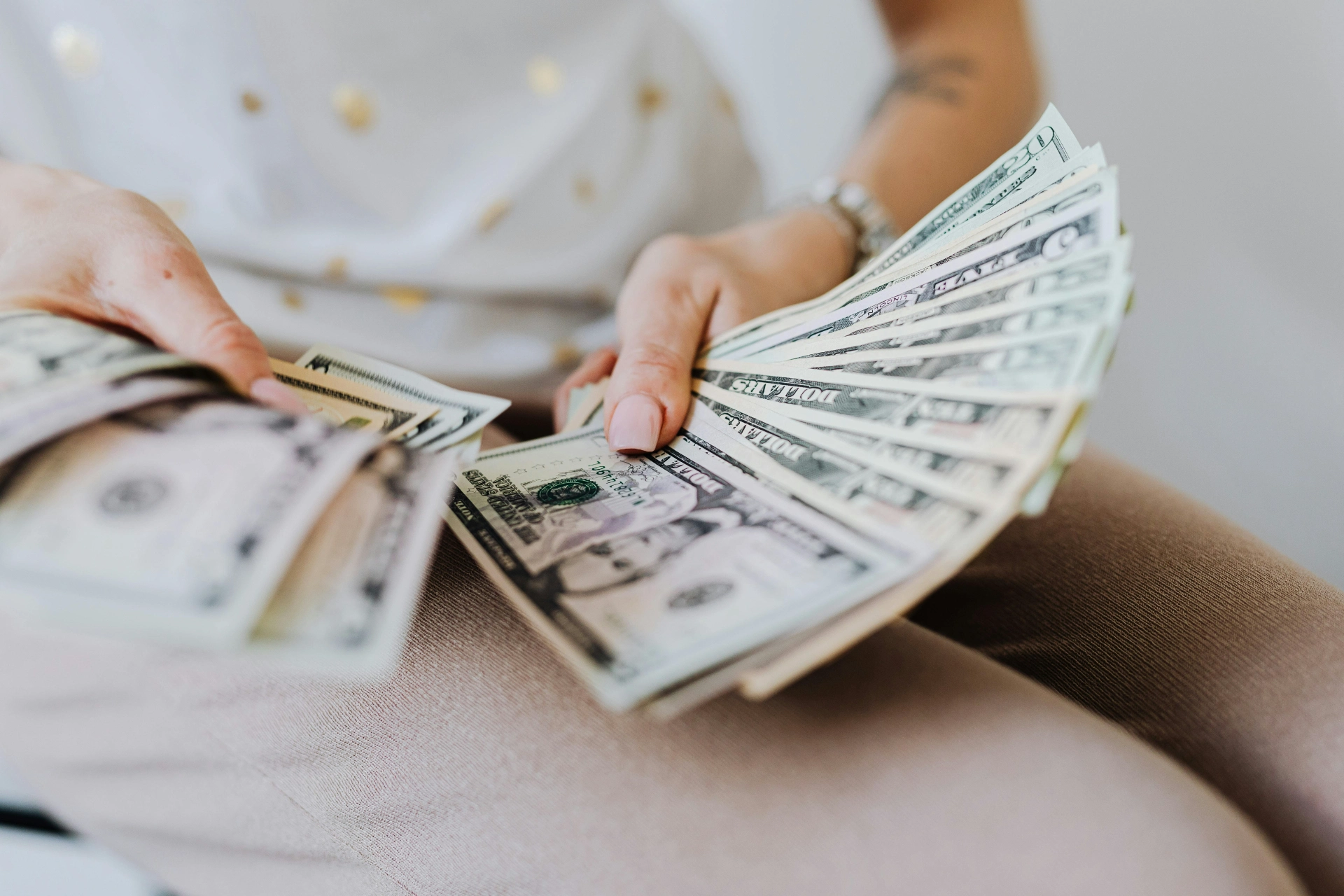 Personne tenant une liasse de billets en dollars américains.