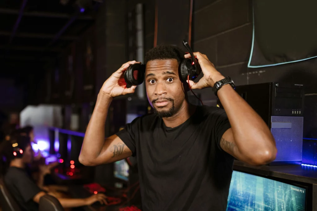 Homme tenant un casque audio sur ses oreilles dans un environnement technologique. Titre : Préparation pour une session a