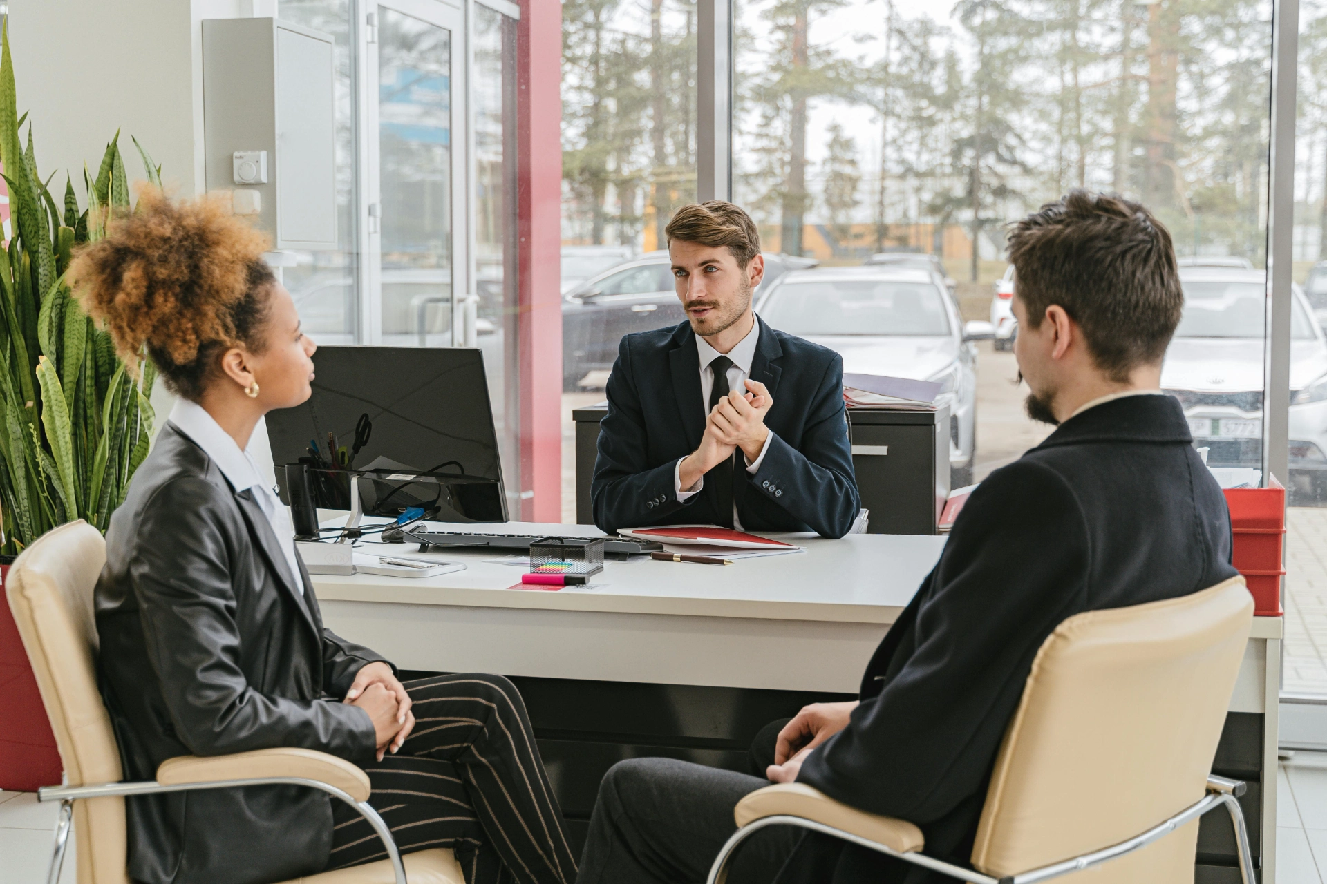 Trois professionnels en réunion dans un bureau moderne, discutant autour d’un bureau.