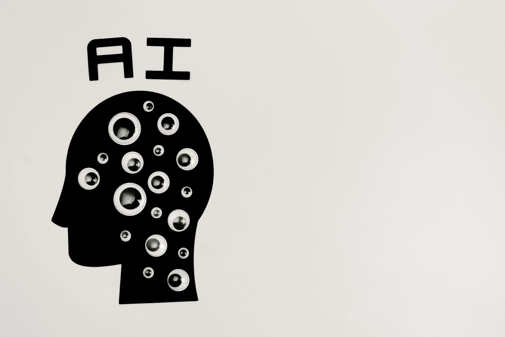 Illustration d’une tête humaine noire remplie d’yeux et du texte « AI » sur fond blanc.