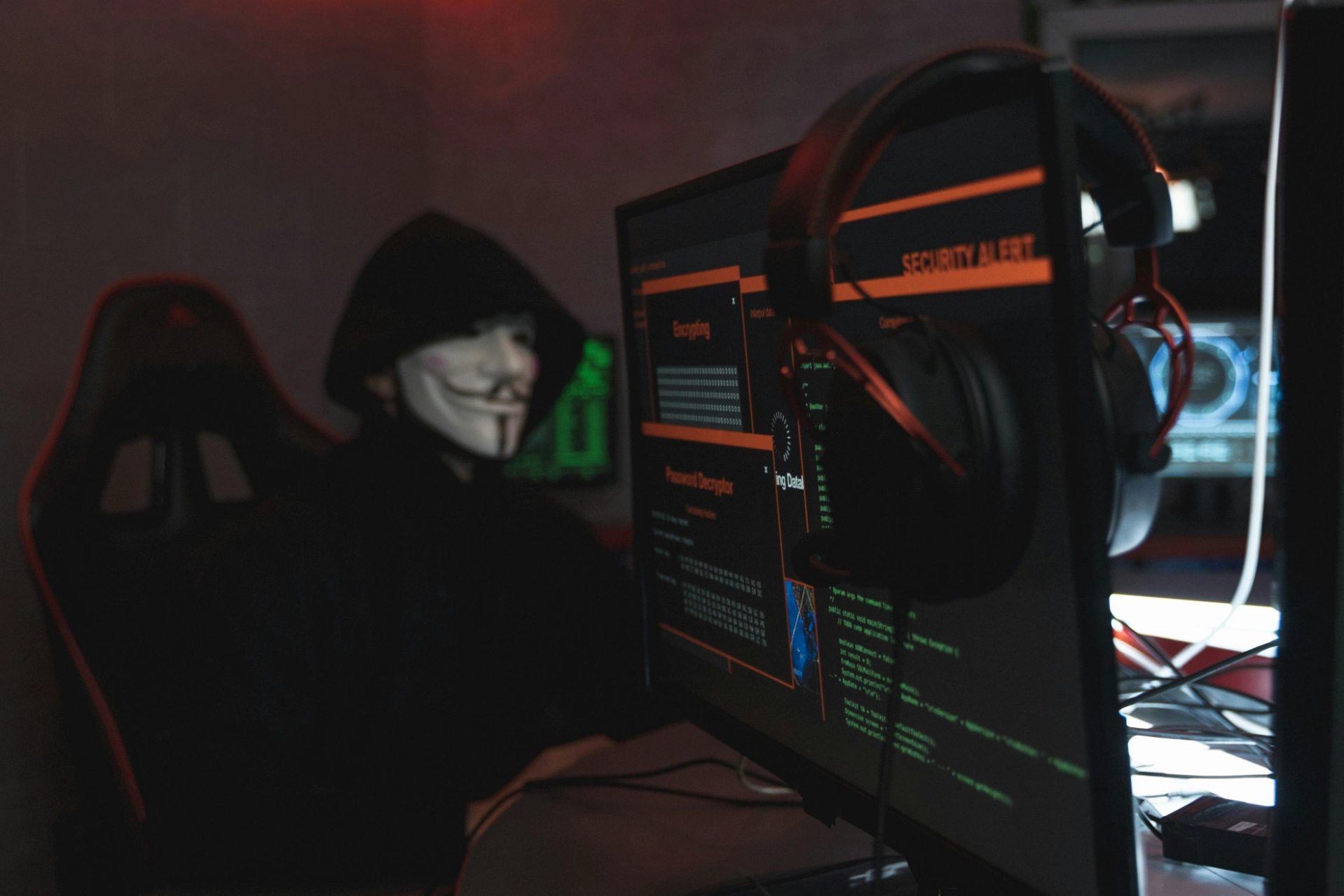 Personne portant un masque de hacker devant un écran d’ordinateur affichant des alertes de sécurité.