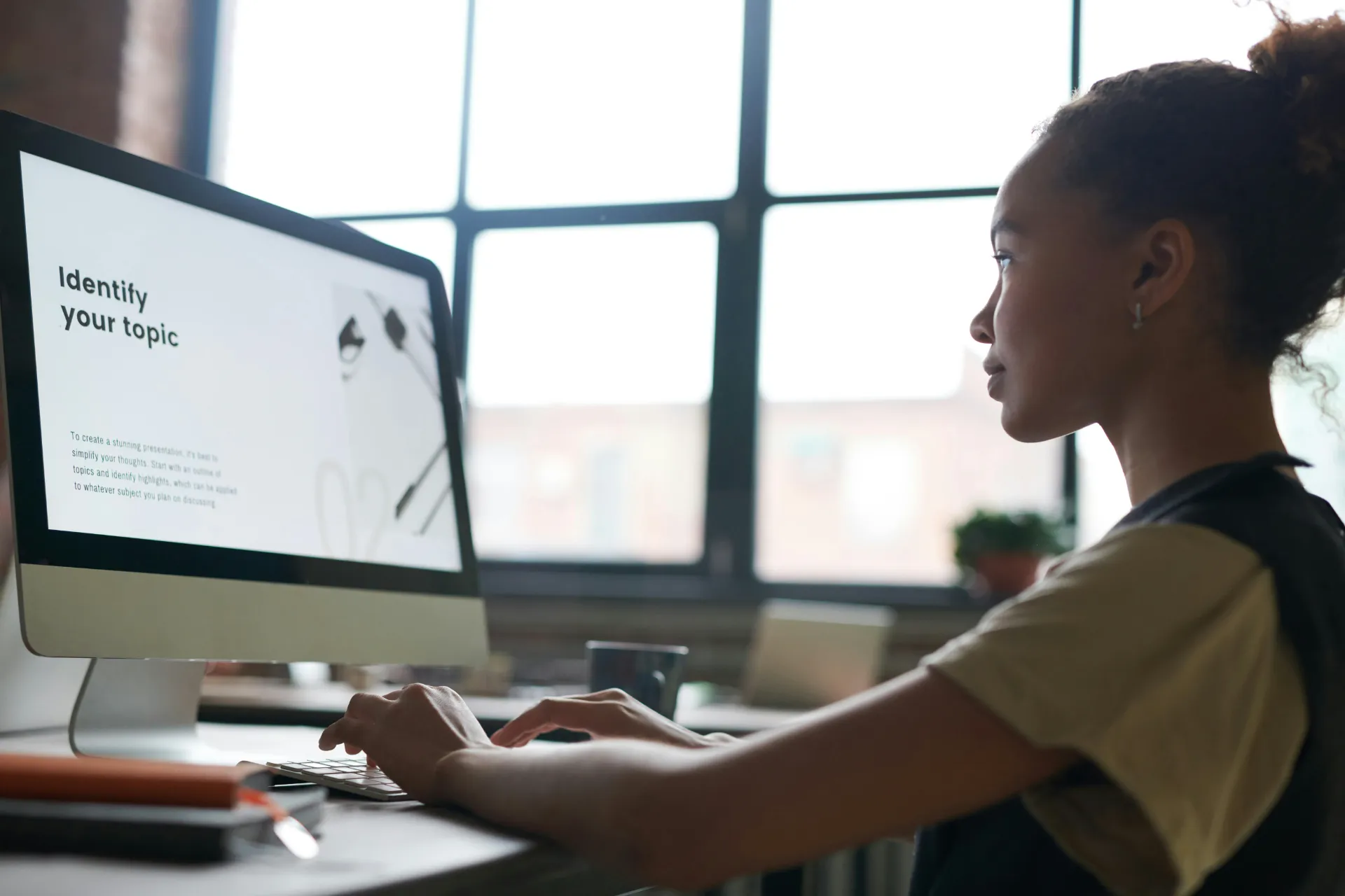 Jeune femme travaillant sur un ordinateur fixe dans un bureau lumineux.
