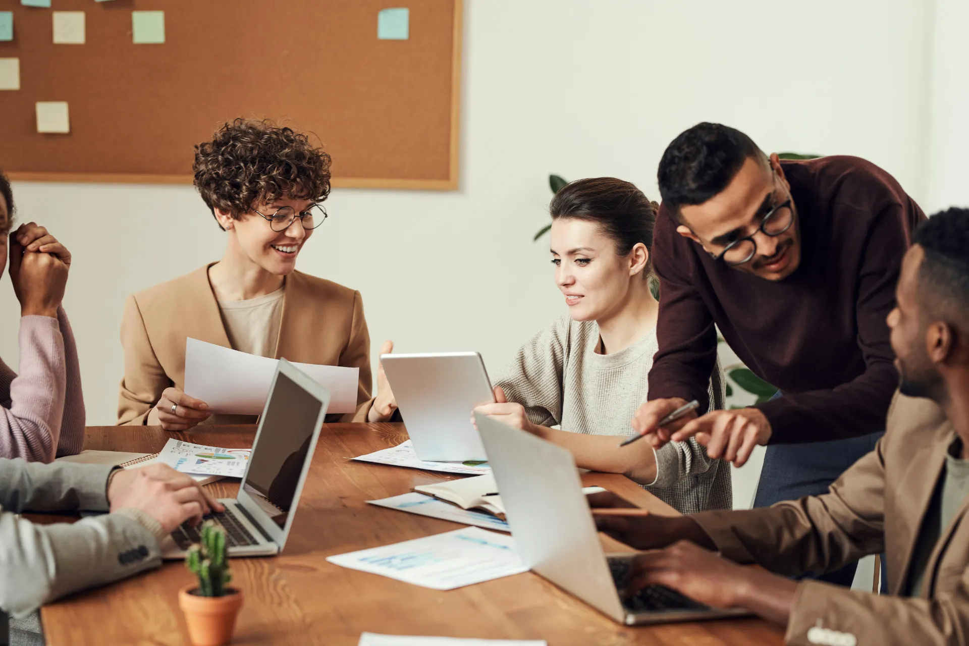 Groupe de jeunes professionnels en réunion, échangeant autour de documents et d’ordinateurs portables.