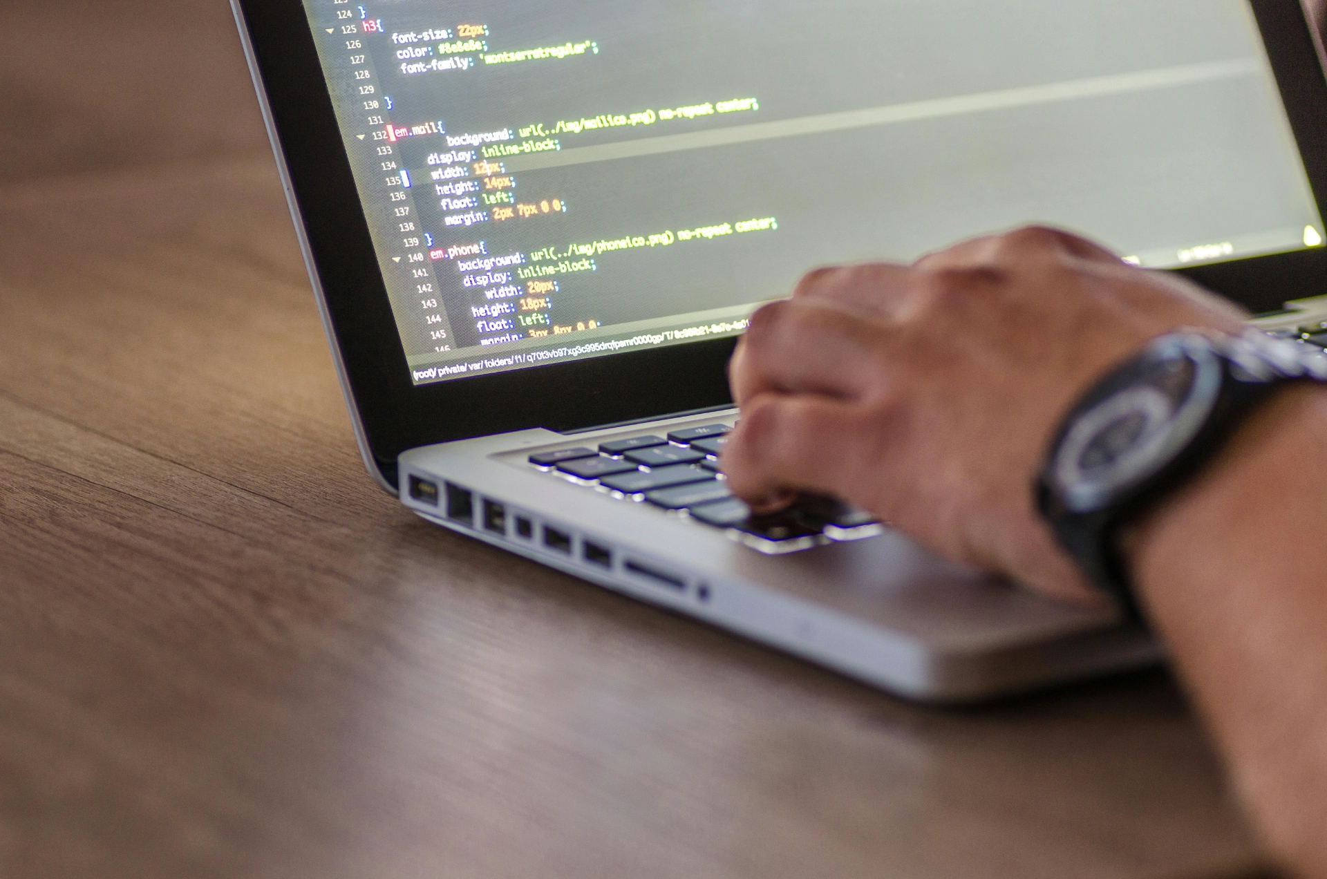 Main d’un développeur tapant du code sur un ordinateur portable.