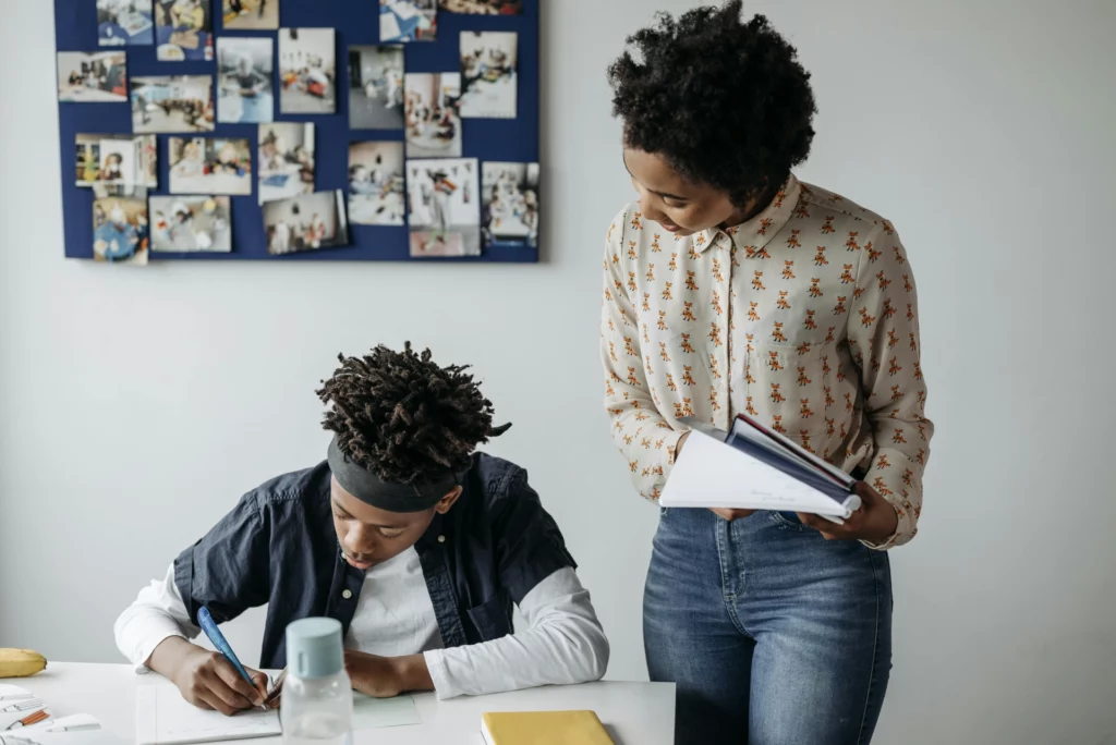 Une enseignante aide un élève à faire ses devoirs en classe.