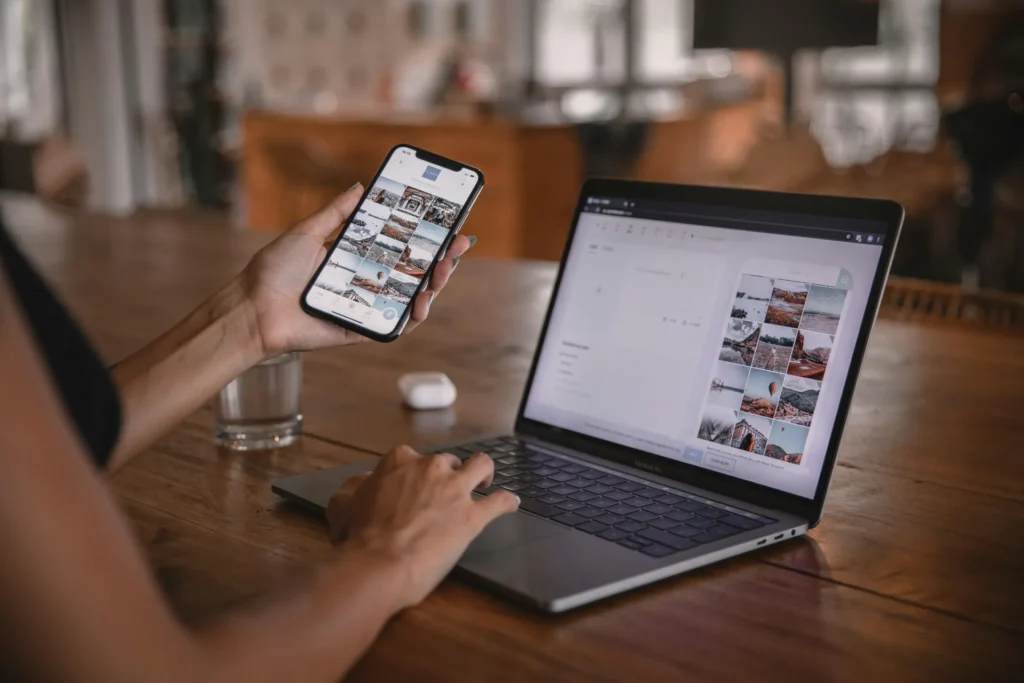 Personne utilisant un smartphone et un ordinateur portable pour gérer des contenus visuels.