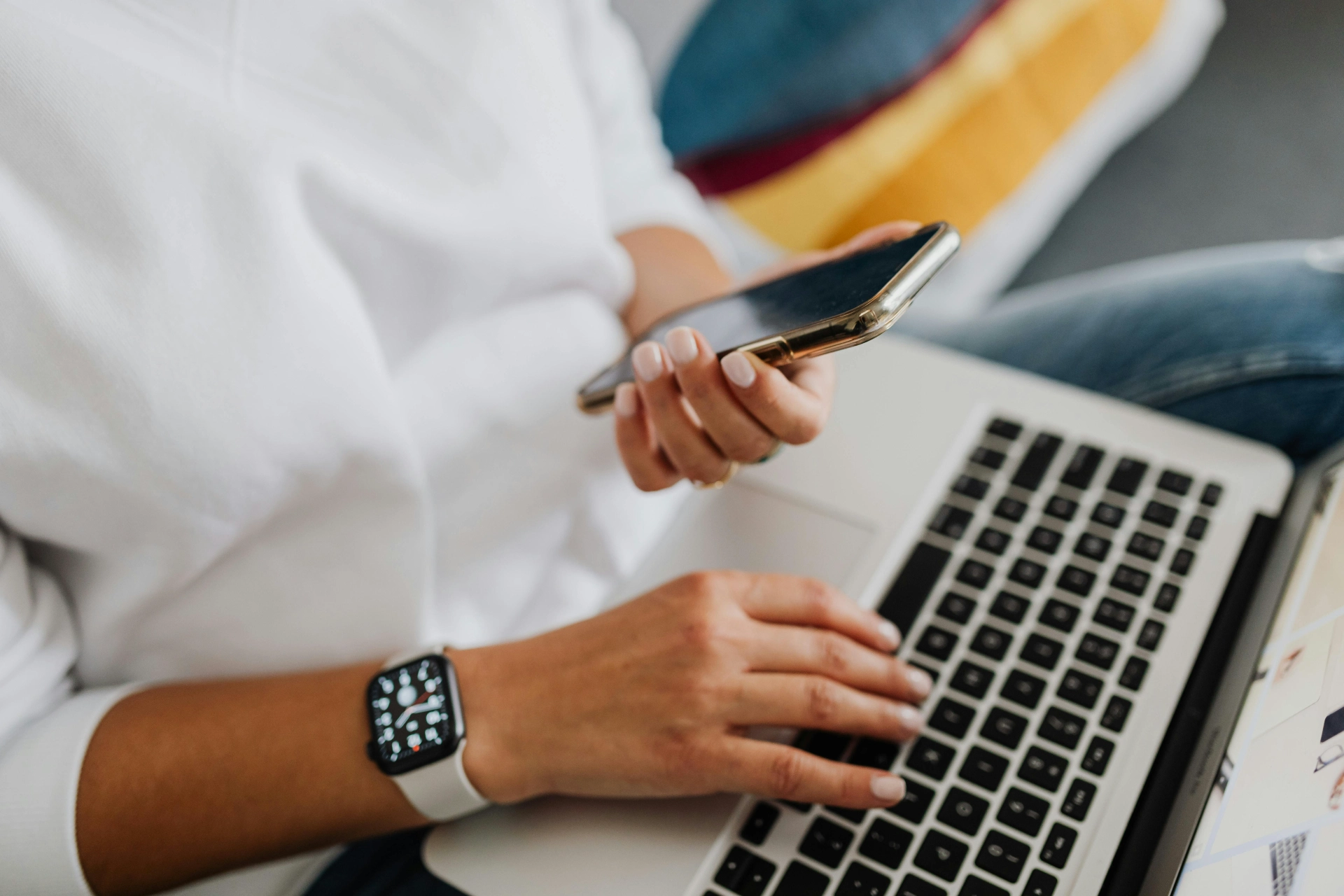 Personne utilisant un ordinateur portable tout en tenant un smartphone.