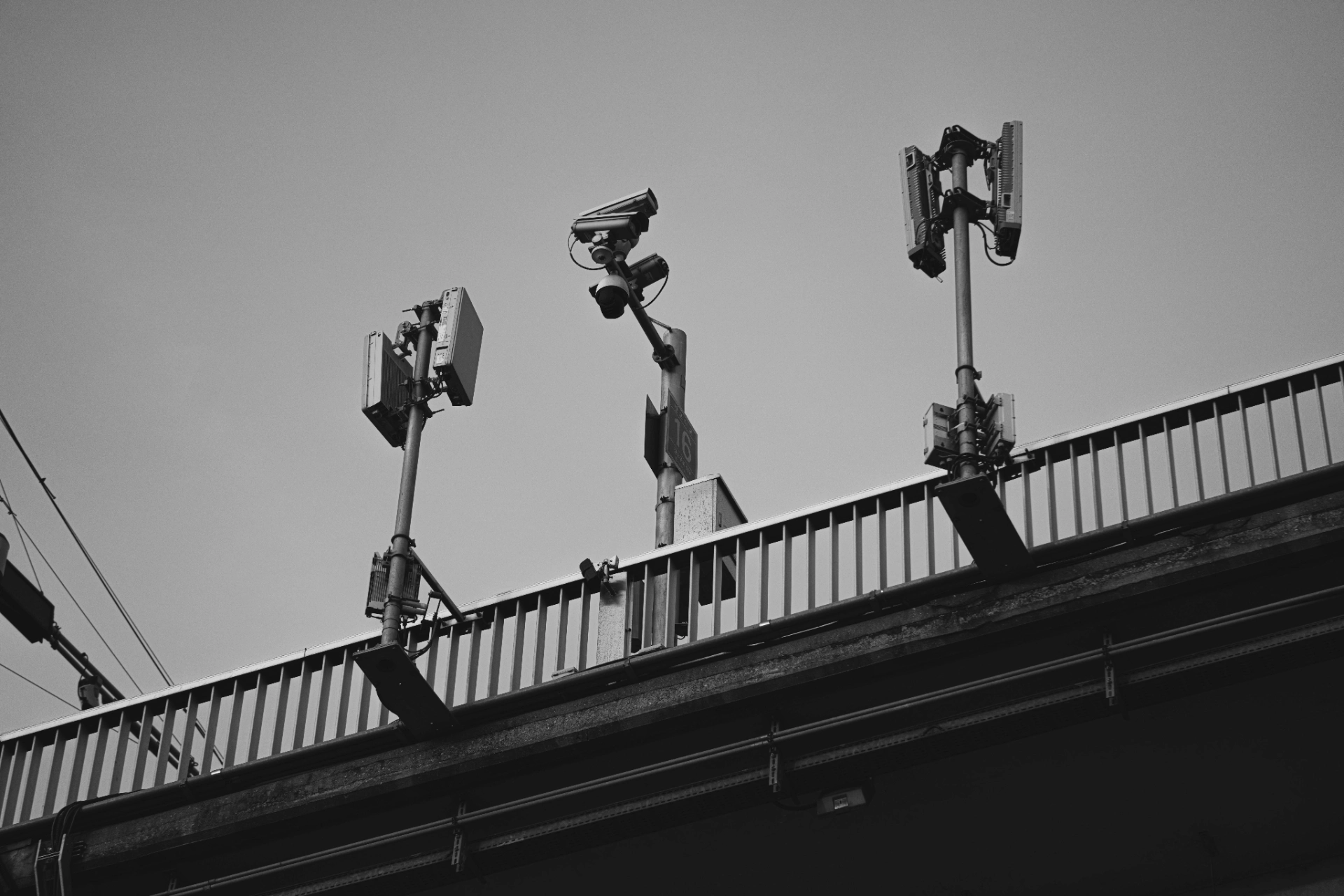 Des caméras de surveillance et des équipements de communication montés sur un pont, observant la zone en dessous.