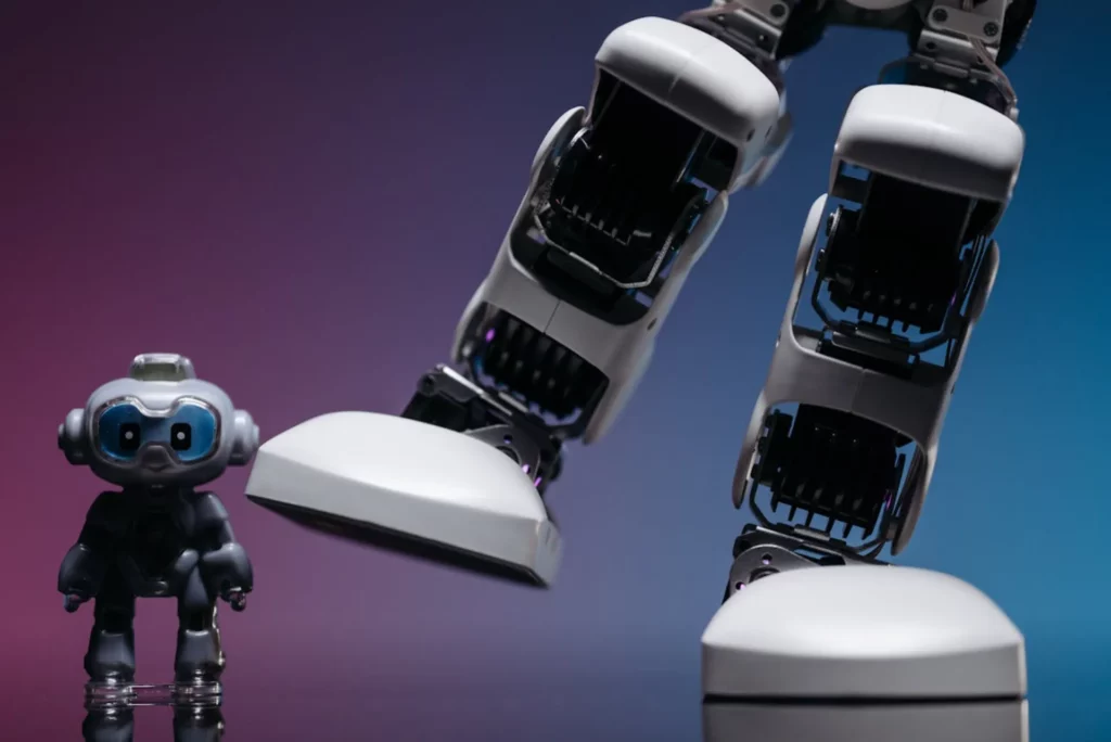 Petit jouet robot à côté de grandes jambes de robot humanoïde sur fond dégradé bleu-violet.