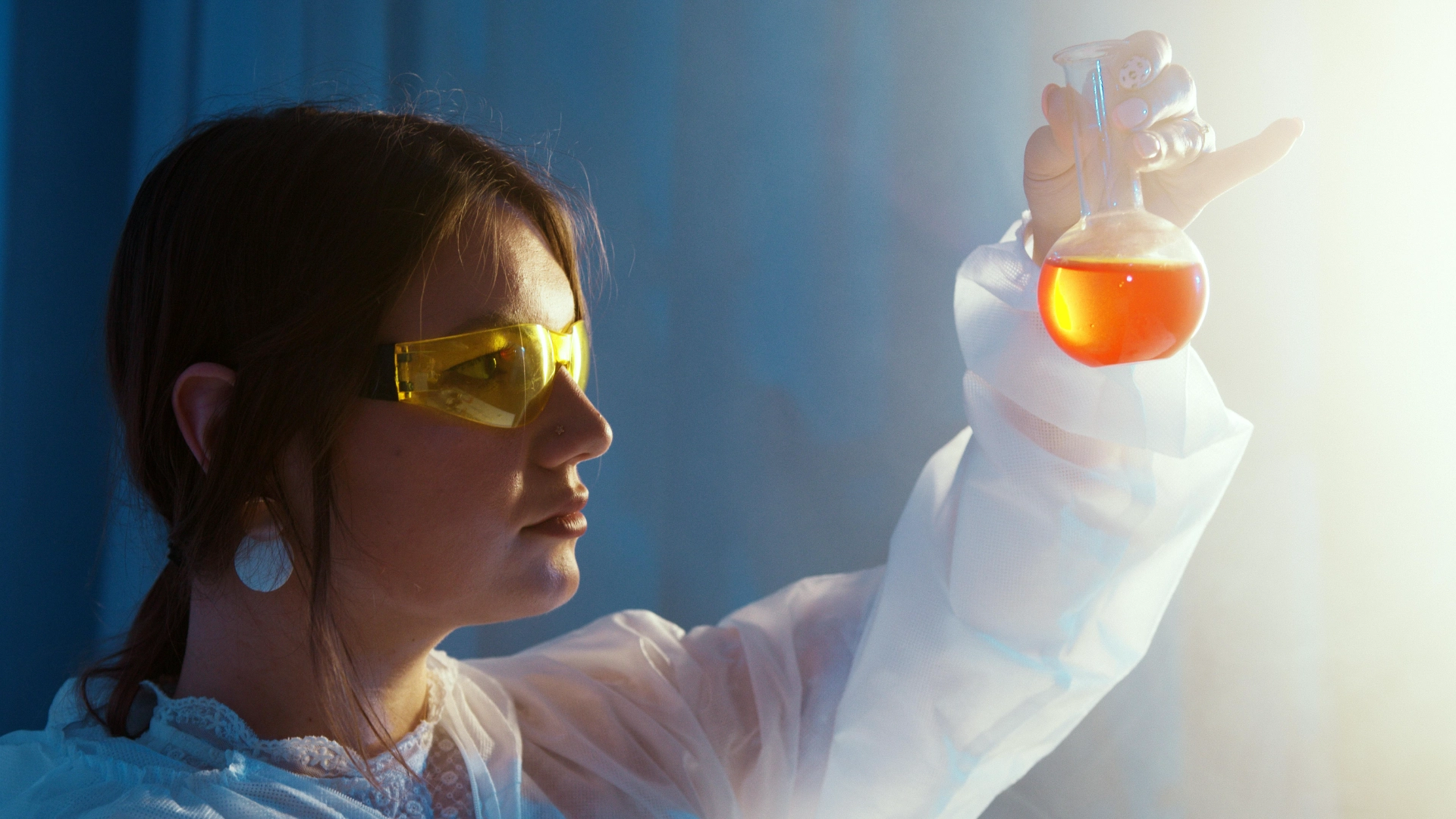 Femme scientifique analysant un liquide orange dans un laboratoire.